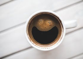 mood boost mental health hustle fitness lessen anxiety today A coffee cup with a smiling face pattern on a wooden table, perfect for morning routines.