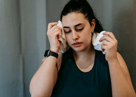 sweat winning session 100% effort hustle fitness belfast join today number 1 gym Woman wiping sweat with a towel, taking a break after an intense gym workout, feeling tired.