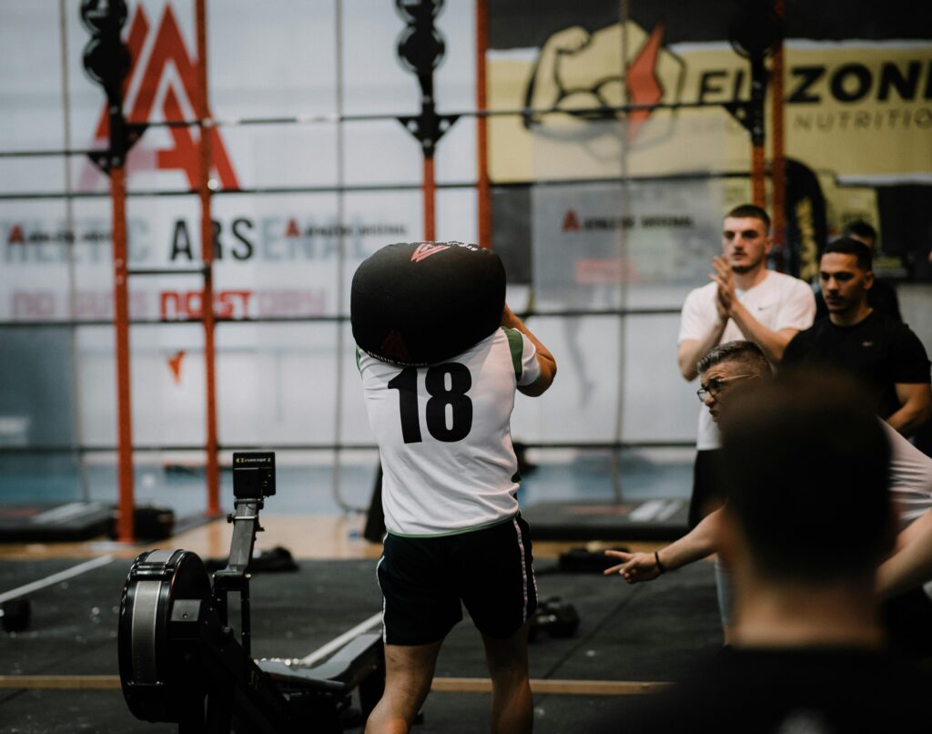 Athlete lifting a sandbag during a dynamic workout session in a gym, showcasing strength and focus.