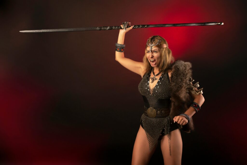 A powerful image of a female warrior in costume wielding a sword, captured in a dramatic studio setting.