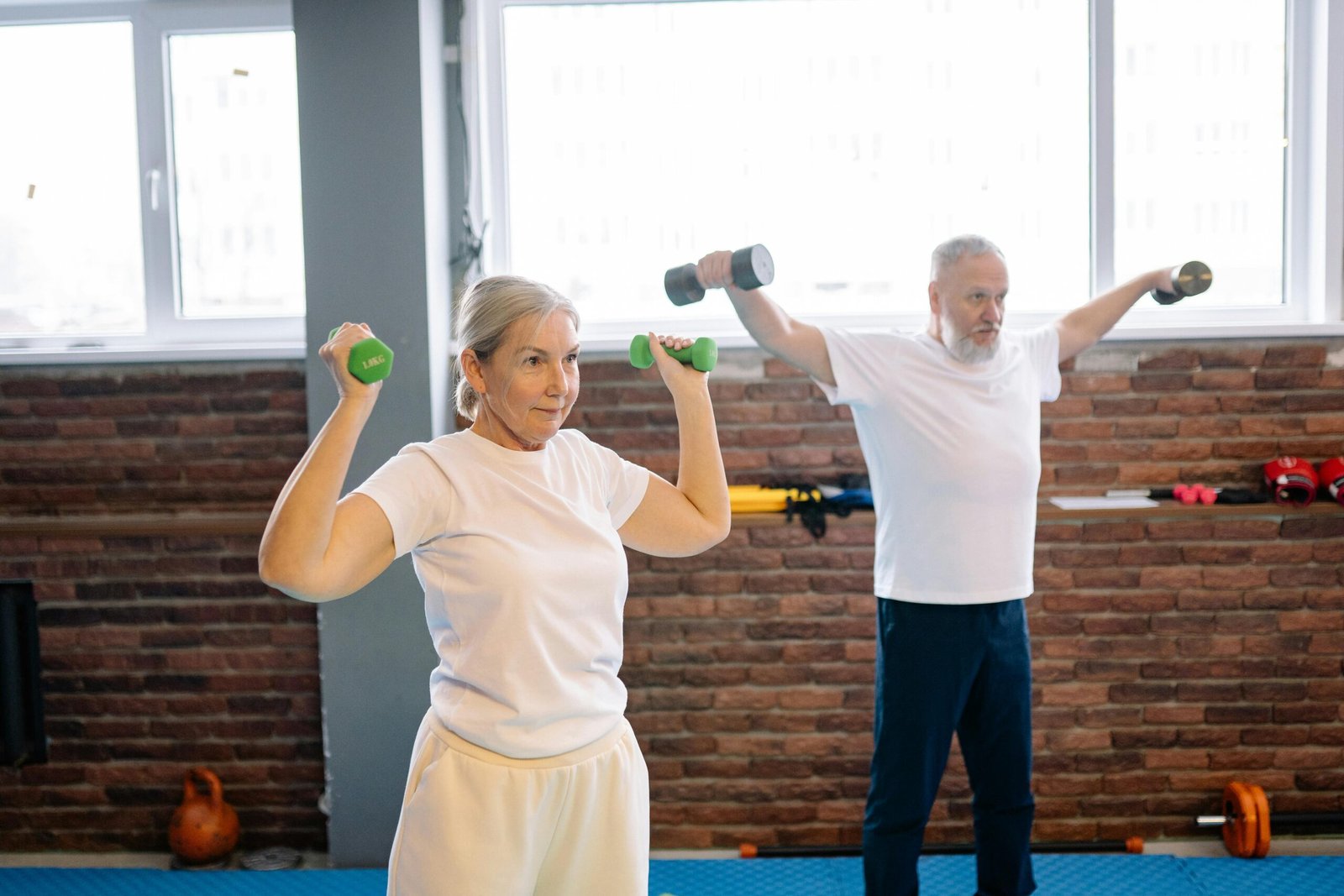 PARTNER WORKOUT GAIN HUSTLE FITNESS BELFAST COMPANY COUPLE WEDNESDAYS Elderly man and woman workout with dumbbells promoting healthy lifestyle and fitness.